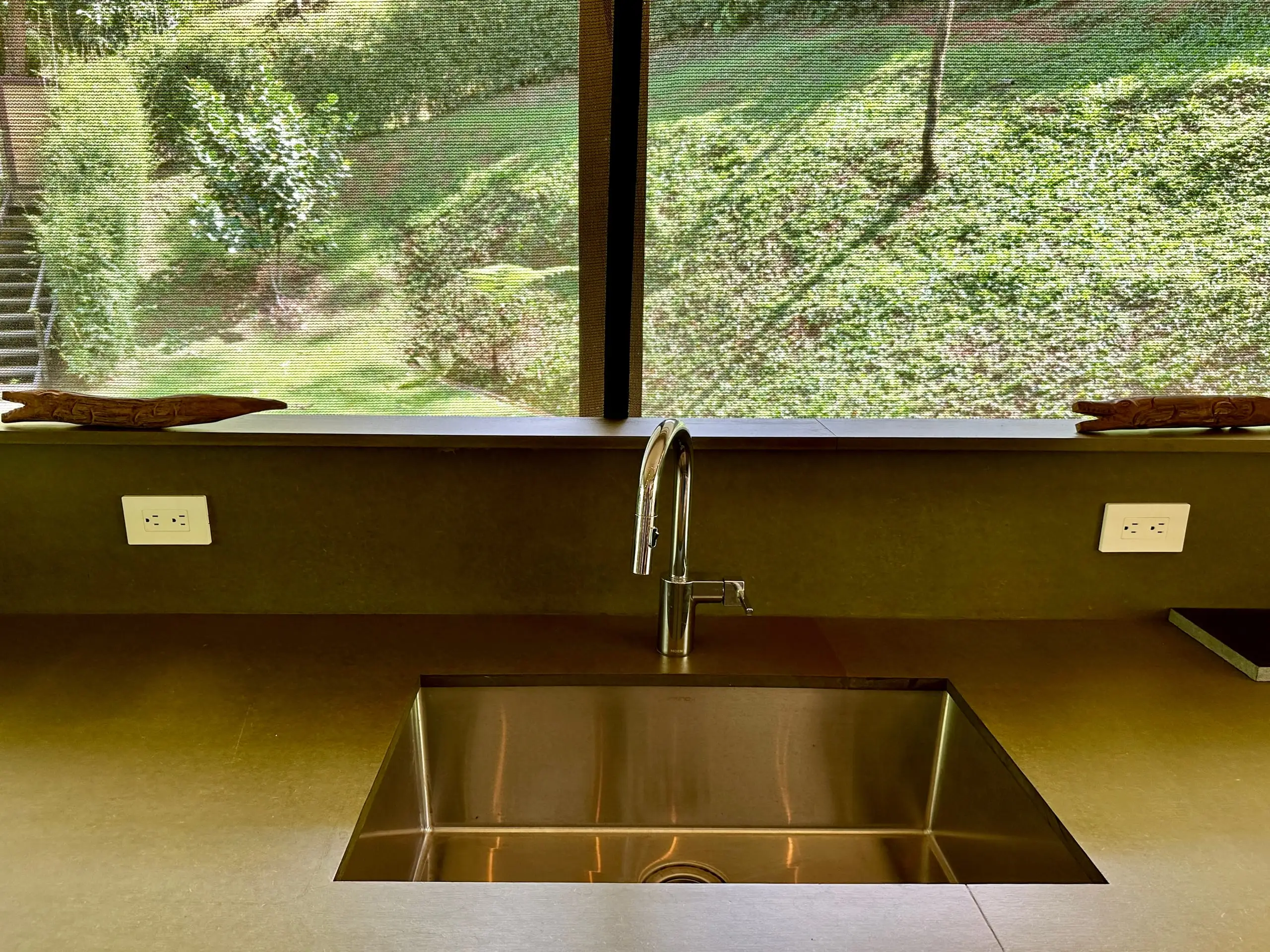 The kitchen sink beneath a window looking onto the green hillside