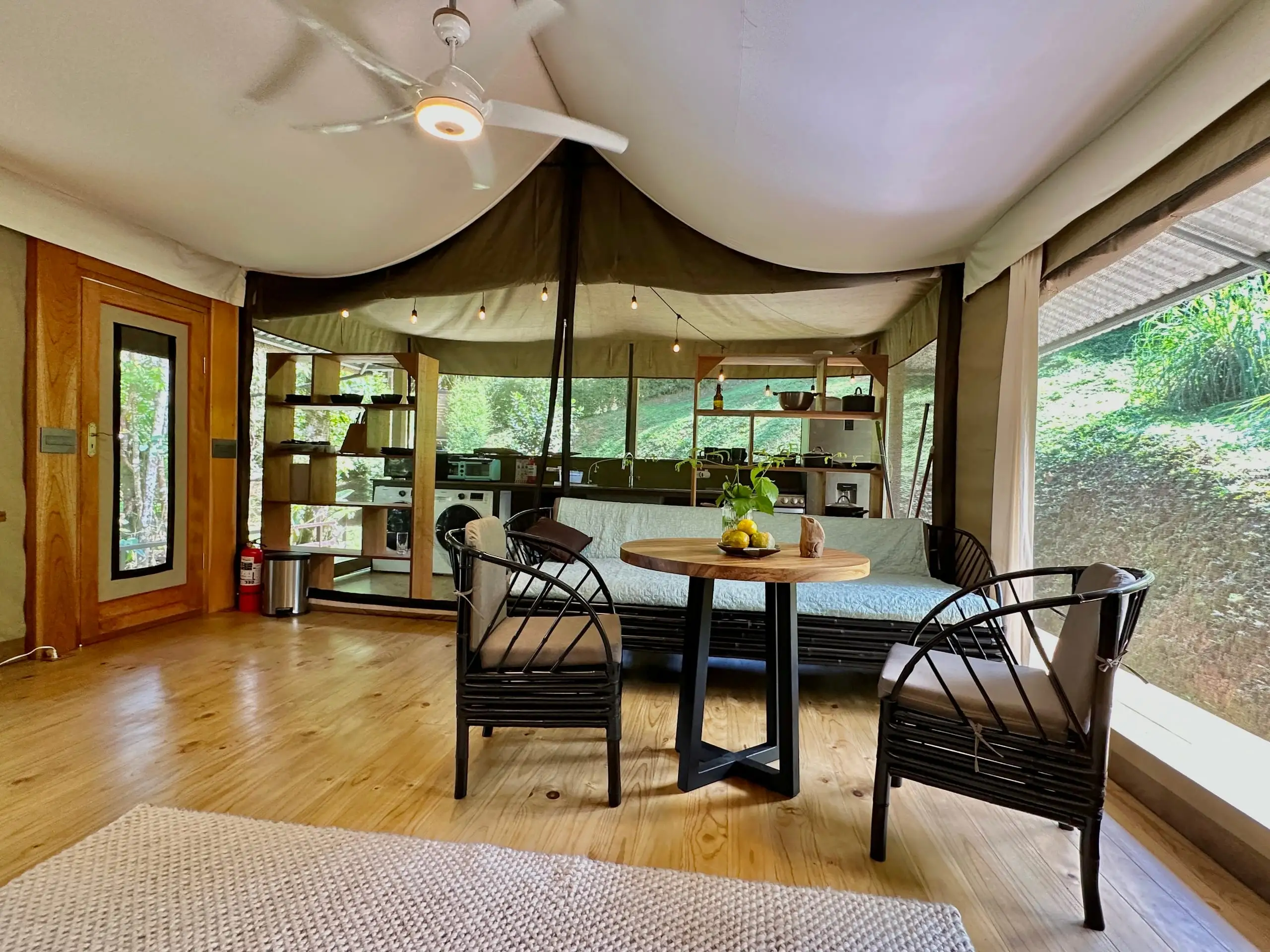 Two woven chairs and a round table by the open canvas wall