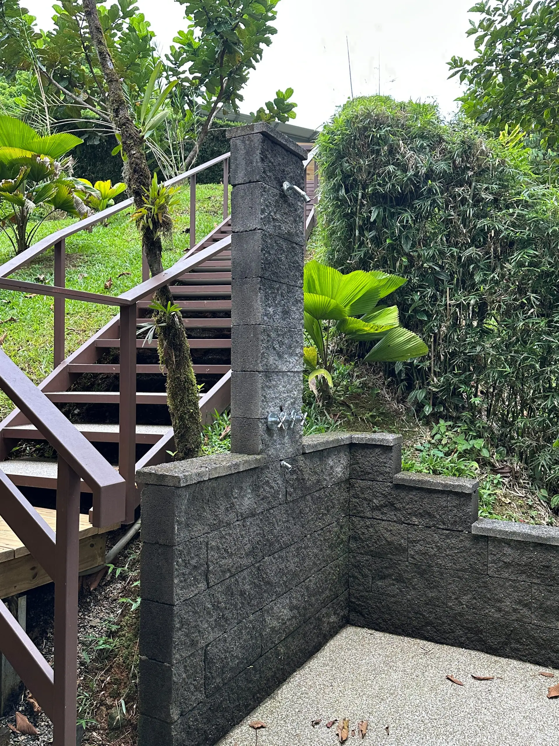 The outdoor shower at the foot of the stairs, walled in stone with the tap set into the pillar