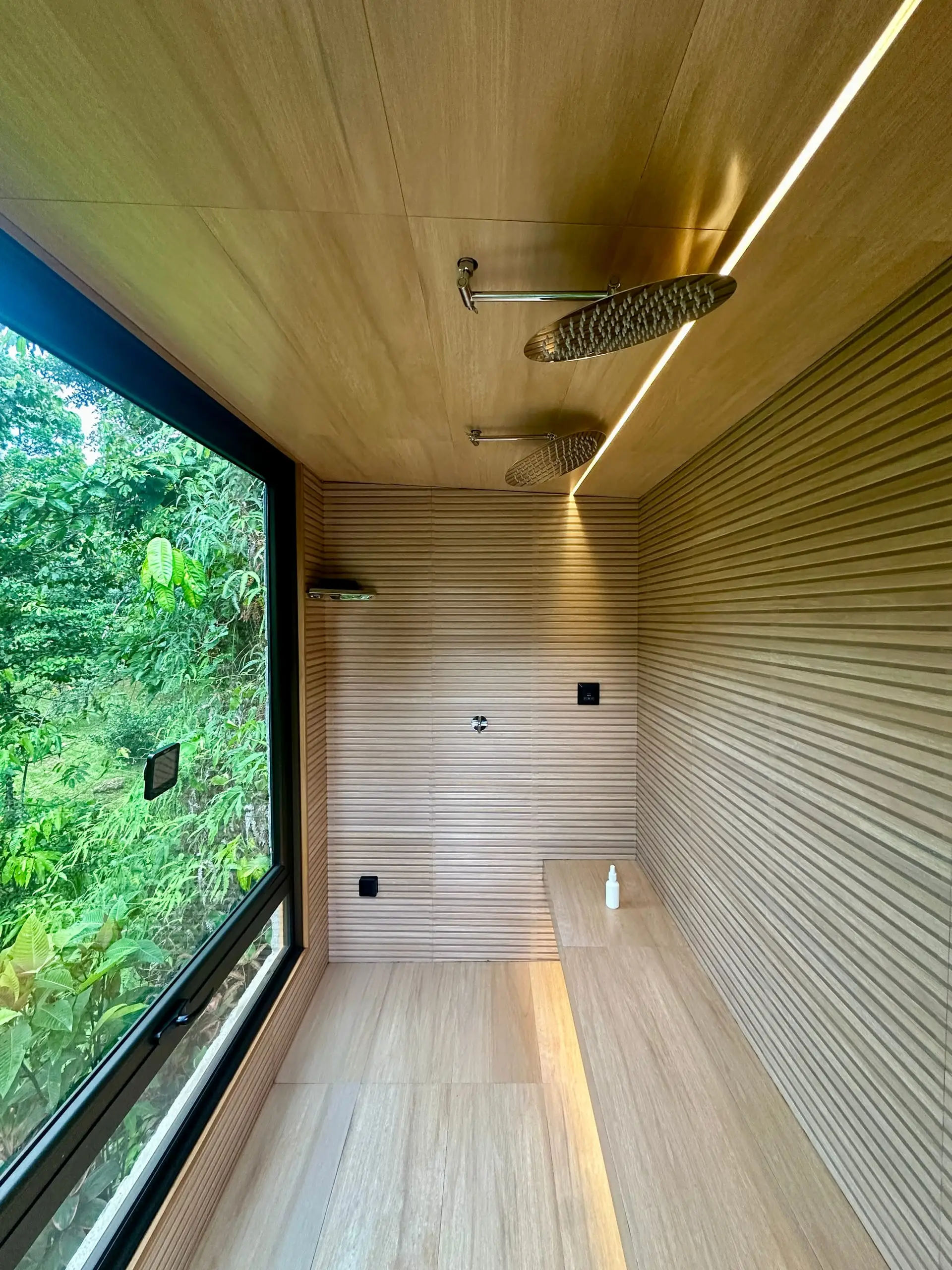 Inside the steam room, its walls in timber-look porcelain tile and its window full of green